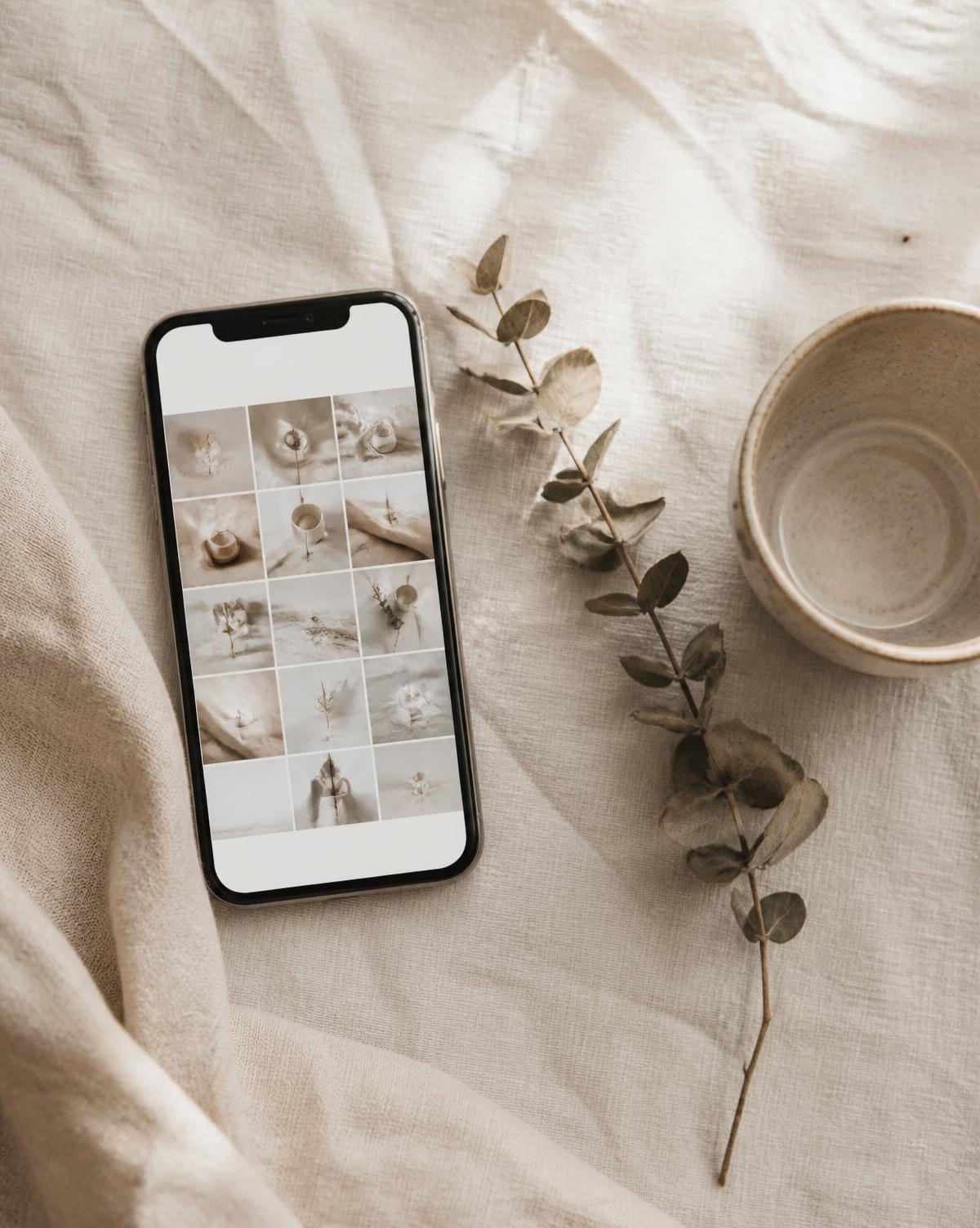 Flat lay of a phone showing a neutral-toned social feed on linen